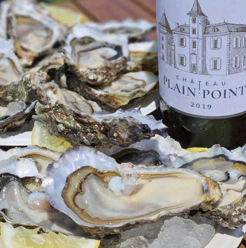 Plateau d'huîtres fraîches ouvertes avec quartiers de citron, accompagné d'une bouteille de vin Château Plain-Point 2019 lors d'une prestation traiteur haut de gamme Dimanch'Huîtres.
