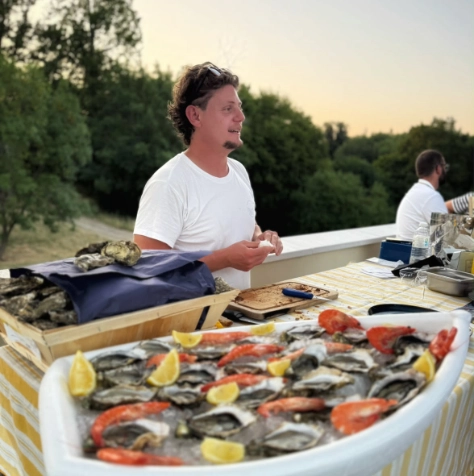 Écailler devant une barque d'huîtres et de crevettes au bord du Bassin d'Arcachon
