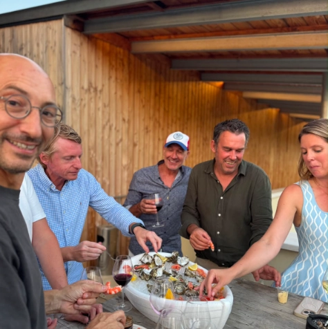 Invités souriants partageant un plateau d'huîtres fraîches et de crevettes lors d'une dégustation haut de gamme signée Dimanch'Huîtres. Ambiance conviviale et chaleureuse pour un séminaire ou un événement privé au Cap Ferret, dans un cadre élégant typique du Bassin d'Arcachon.