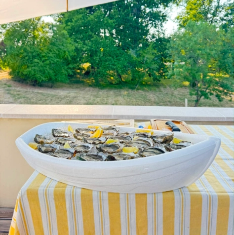 Présentation d'huîtres fraîches ouvertes sur lit de glace et citrons dans une barque blanche signée Dimanch'Huîtres. Buffet traiteur haut de gamme et animation écailler pour un mariage ou un événement privé chic autour du Bassin d'Arcachon.