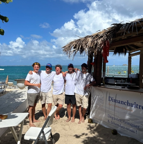 L'équipe de Dimanch'Huîtres réunie sur la plage devant son comptoir de bar à huîtres éphémère. Une animation traiteur de la mer originale et haut de gamme les pieds dans le sable, disponible pour vos mariages et réceptions privées en Gironde.