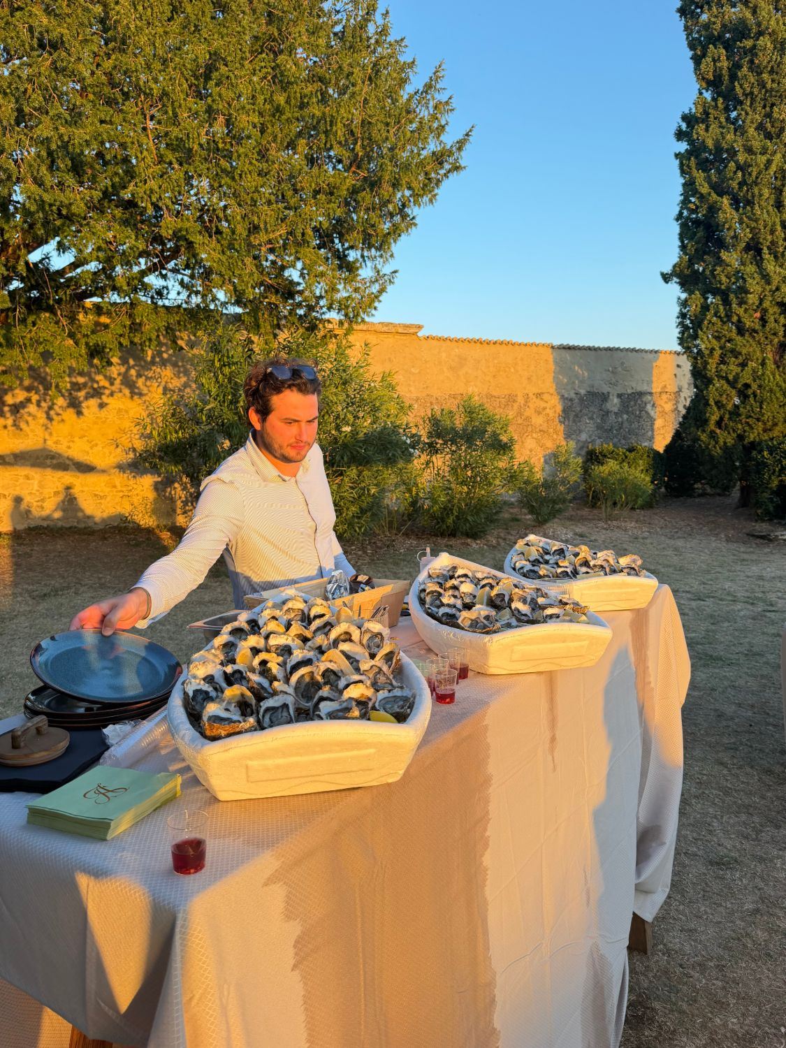 Écailler qui dresse son bar à huîtres dans le parc d'un domaine avant l'arrivée des invités