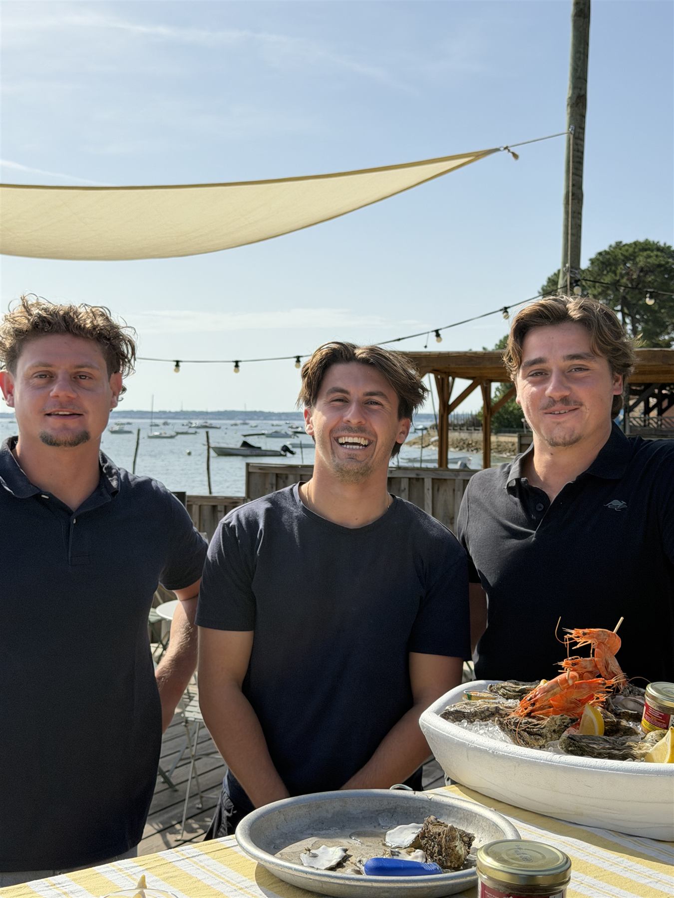 Les trois associés de Dimanchuitres derrière leur comptoir au bord du Bassin d'Arcachon
